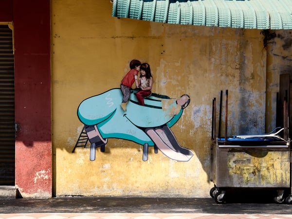 Boy and girl in a dog head slide street art, Penang, Malaysia
