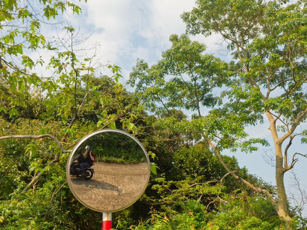 Selfie in circular mirror around a curve, on the back of a motorbike, Da Nang, Vietnam