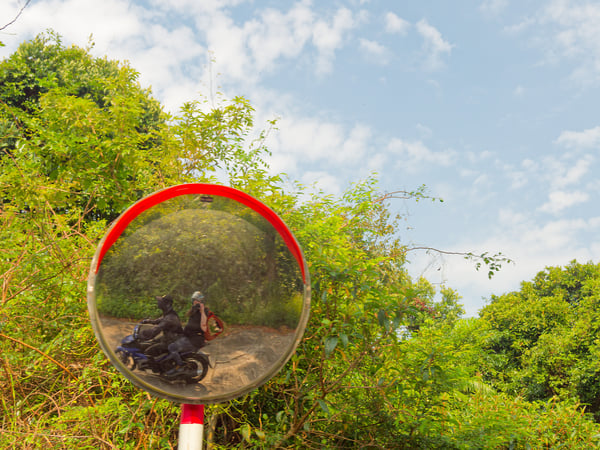 Selfie in circular mirror around a curve, on the back of a motorbike, Da Nang, Vietnam