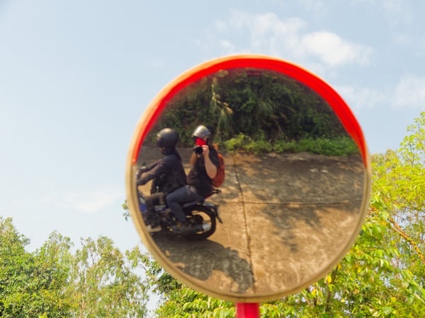 Goodbye selfie in circular mirror around a curve, on the back of a motorbike, Da Nang, Vietnam